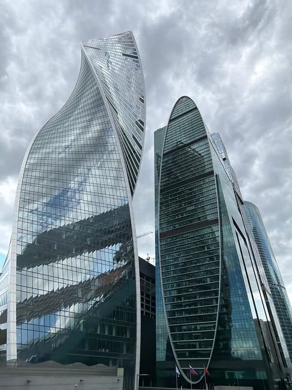 Moscow skyscrapers observed under gray skies, taxi spotted nearby