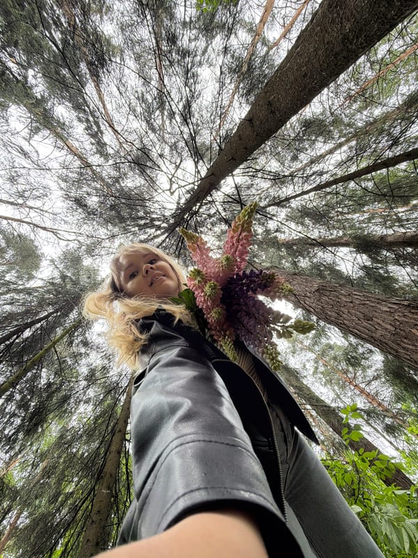 Woman poses with lupine flowers in Chaikovsky forest photoshoot