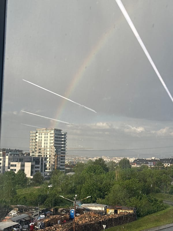 Rainbow appears over Sofia cityscape during afternoon hours