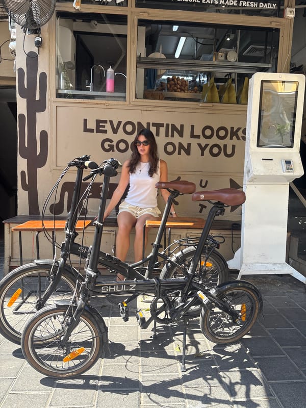 Woman rests on bench near bicycles outside Tel Aviv shop