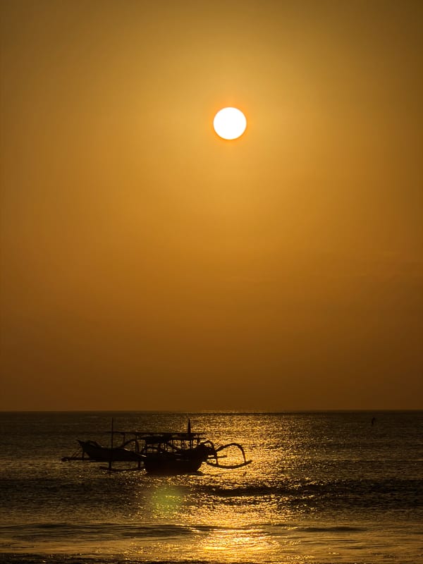 Golden hour at Kuta Selatan beach, boats, vendors, and crowds