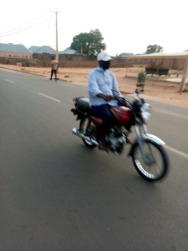 Masked motorcyclist rides through residential area in Tempure, Nigeria