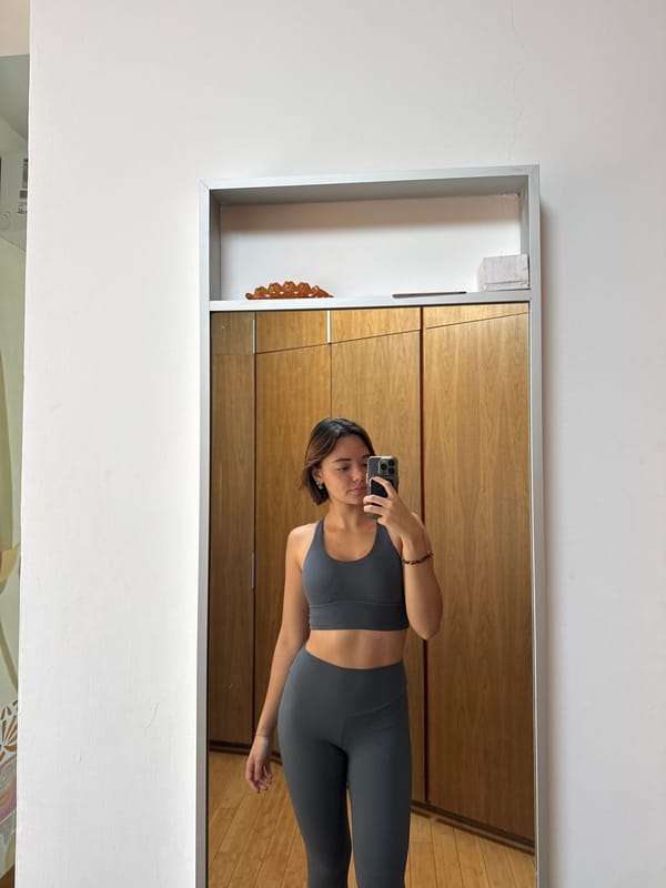 Woman takes mirror selfie in gray athletic wear