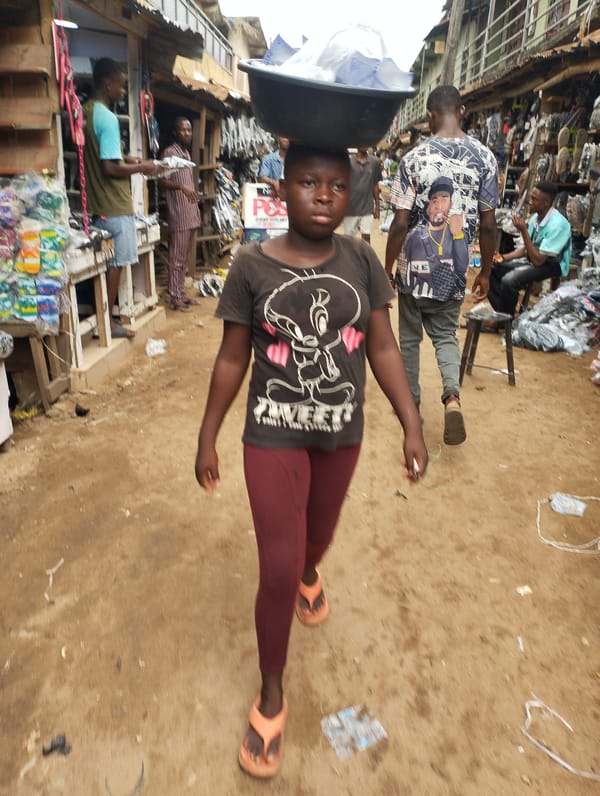 Young person carries bowl through busy Fegge market