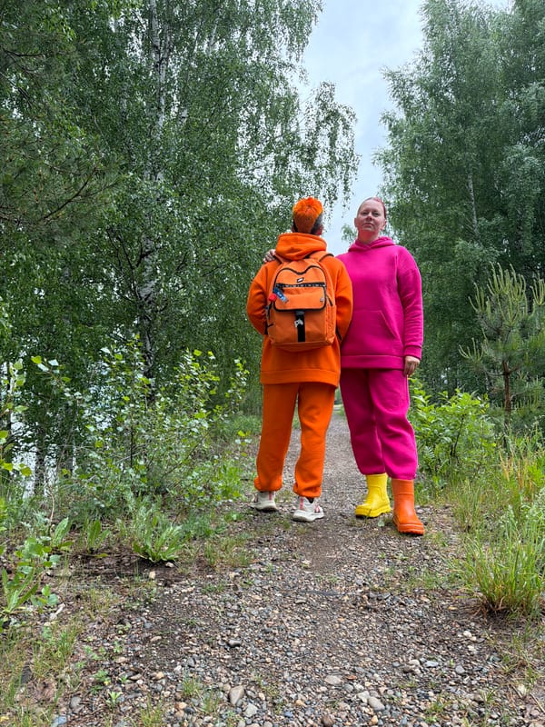 Two people in bright clothing spotted on wooded path