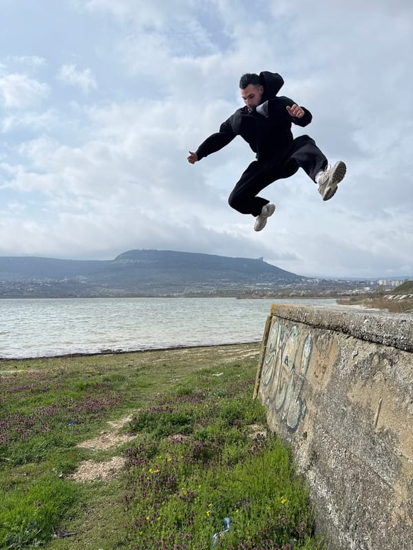 Person jumps mid-air near graffitied concrete structure in Shumen