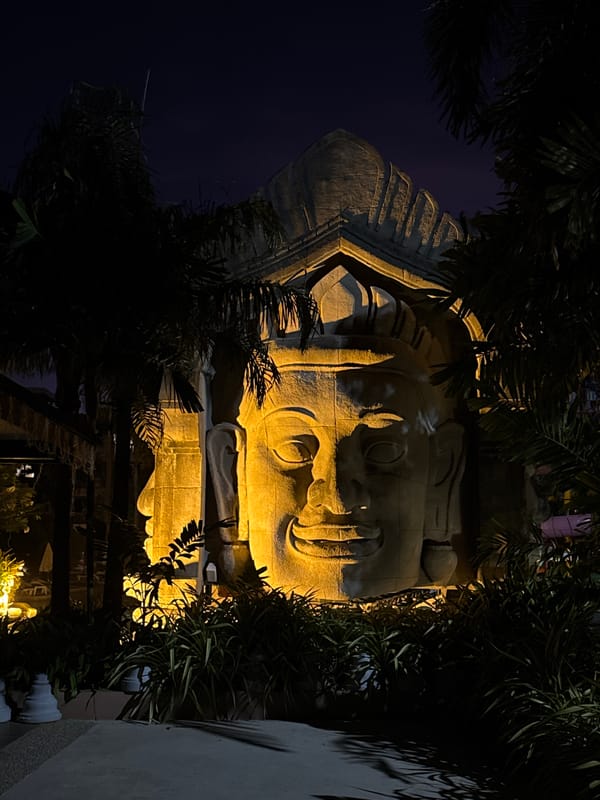 Nighttime Karon: Buddha sculpture and resort pool in full swing