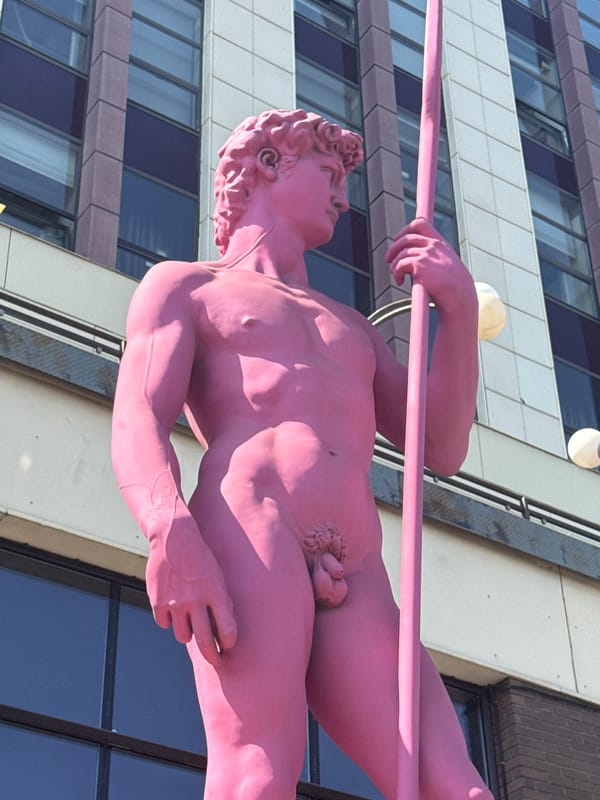 Urban riverside walk: barges, a dam, and a pink statue