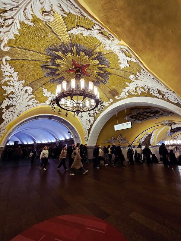 Tourist documents ornate Moscow Metro station architecture during morning commute