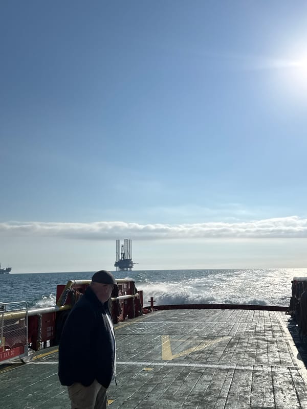 Man observes oil rig from ship deck in Italian waters