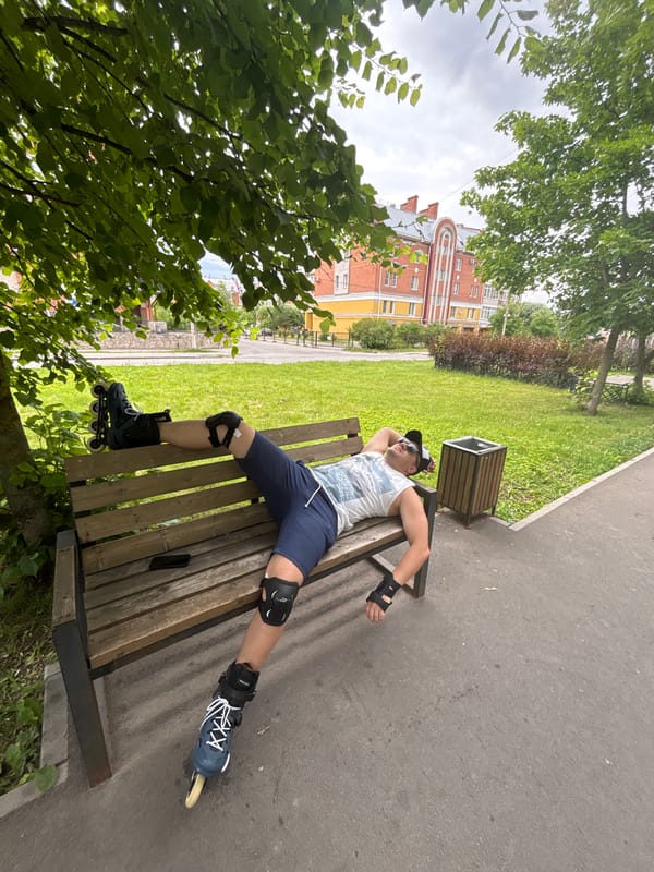 Rollerbladers resting on benches along a shaded urban park path