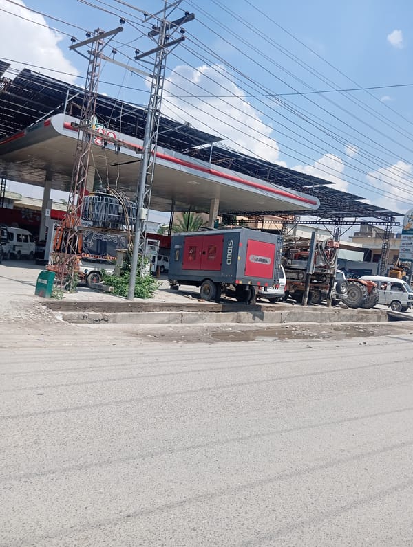 Gas station, fruit stand, and glass building along a commercial strip