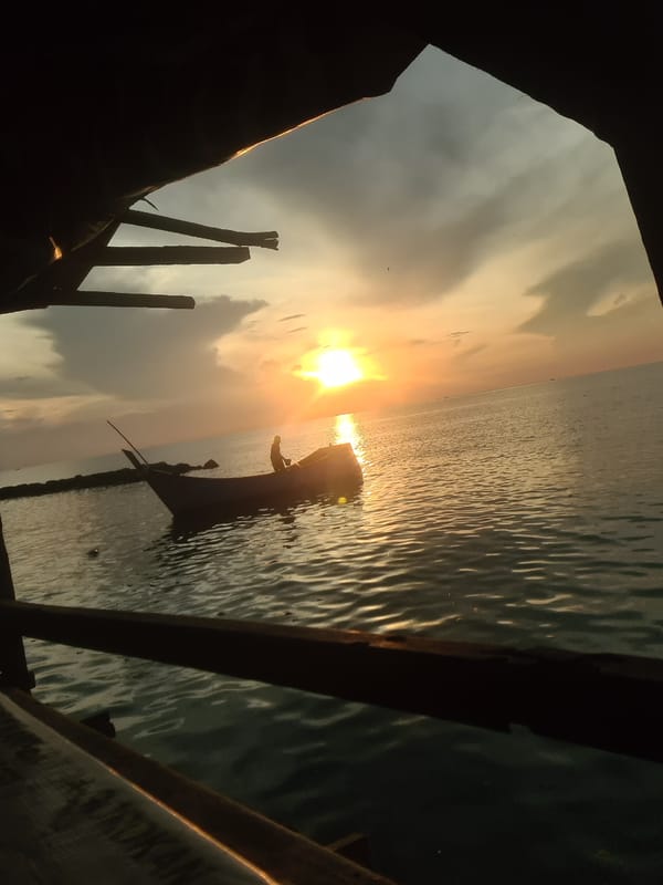 Fishing boats and crew at the Lhokseumawe waterfront during sunset