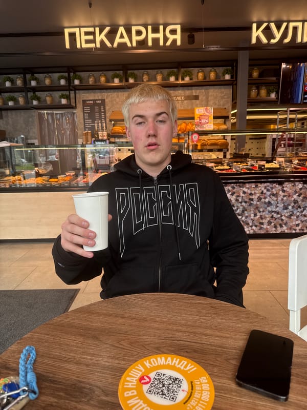 Young man in Russian hoodie observed at cafe table