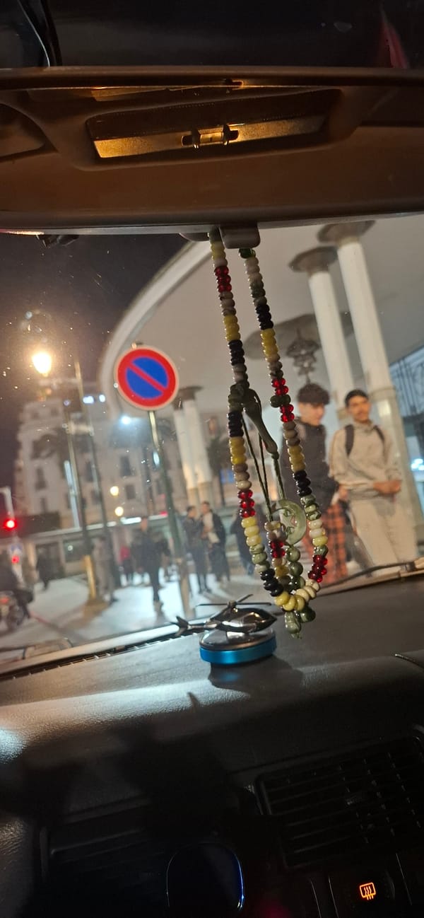 Pedestrians walk along Rabat sidewalk, captured in rearview mirror