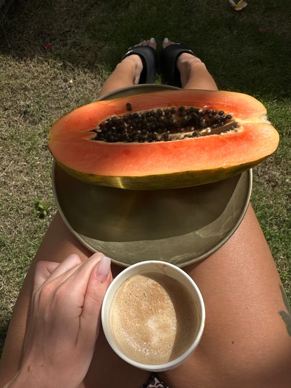 Woman enjoys morning papaya and coffee by pool in Bali