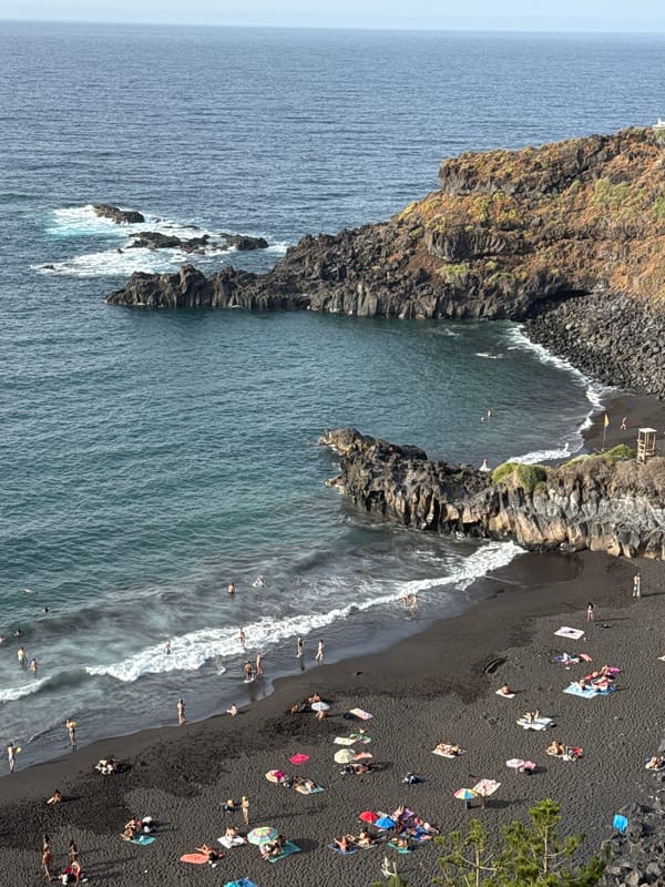 Busy black sand beach, aerial and cliff views