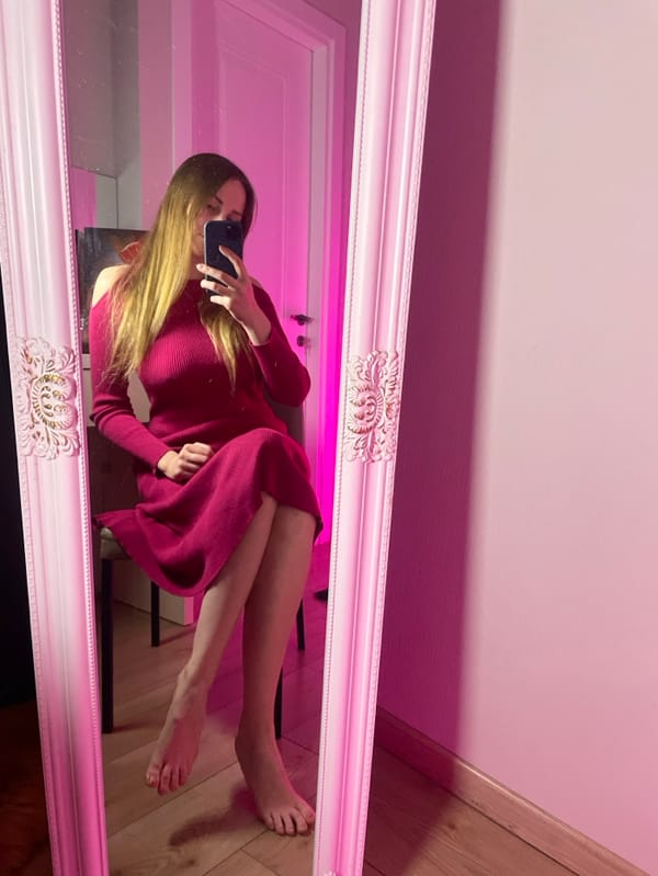 Woman takes mirror selfies in pink-lit room in Batumi