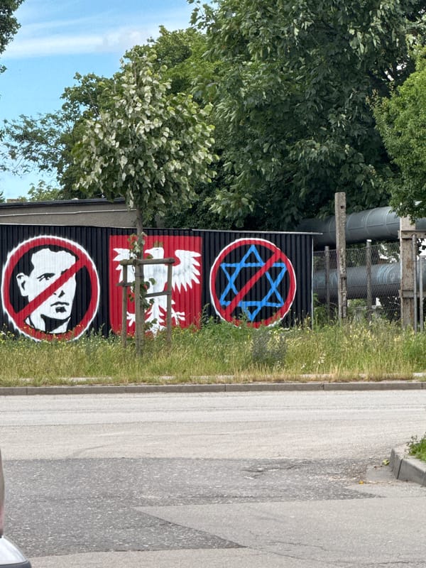Street art tags and stencils on a corrugated fence in Gdańsk