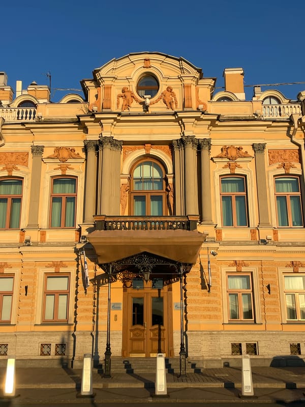 Classical building exterior and a shimmering sunset over water