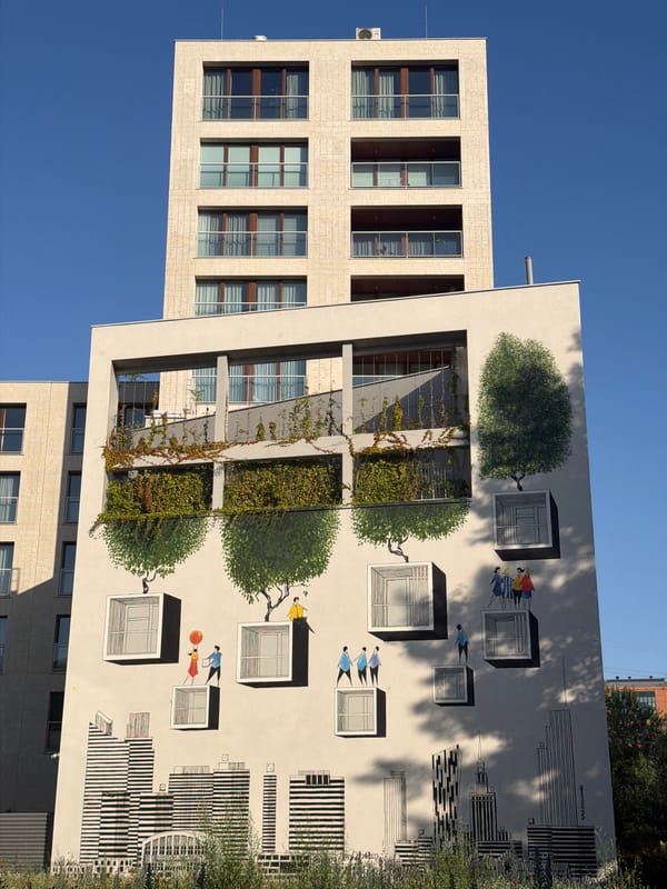 Street-level mural on a modern Warsaw building, sunny day