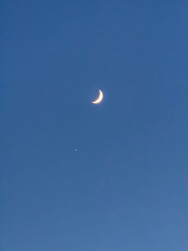 Crescent moon and bright celestial object visible in Krasnoyarsk daytime