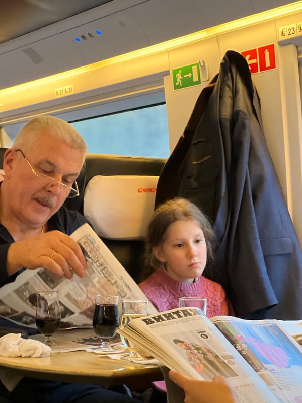 Man reads newspaper with girl on Russian train