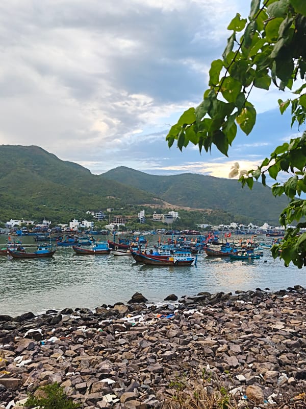 Nha Trang harbor: fishing boats, mountain backdrop, and coastal debris