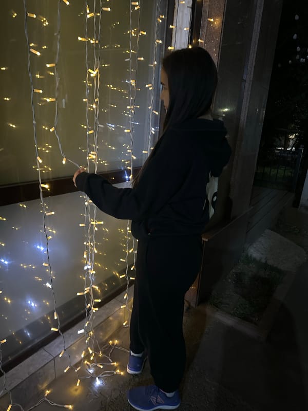 Outside a fairy-lit Almaty entrance in a graphic black hoodie