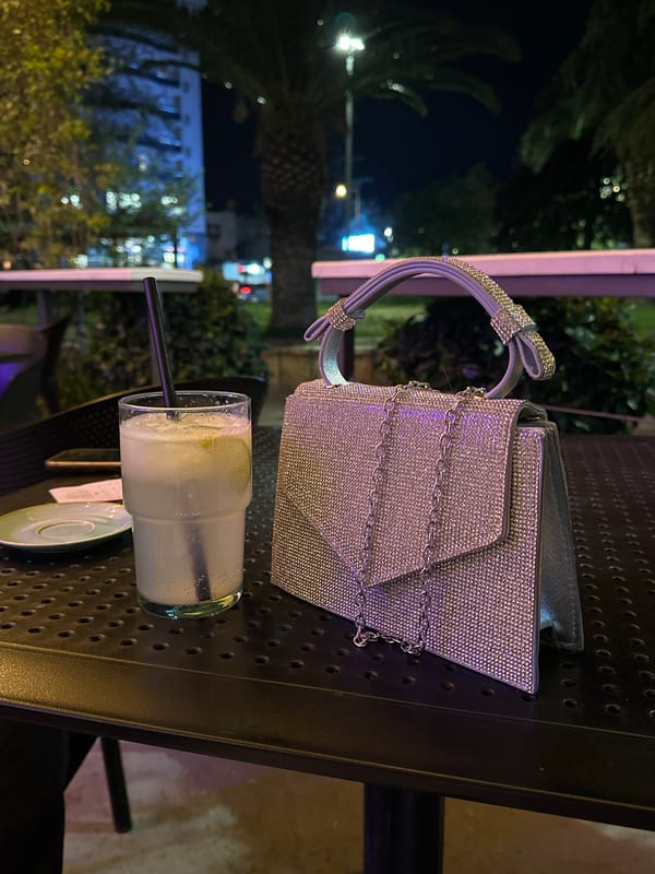 Evening cocktail and handbag captured on metal table in Polje