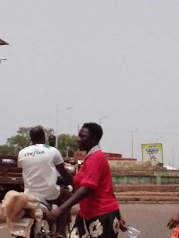 Street scene captured in Tamale with moped rider, woman