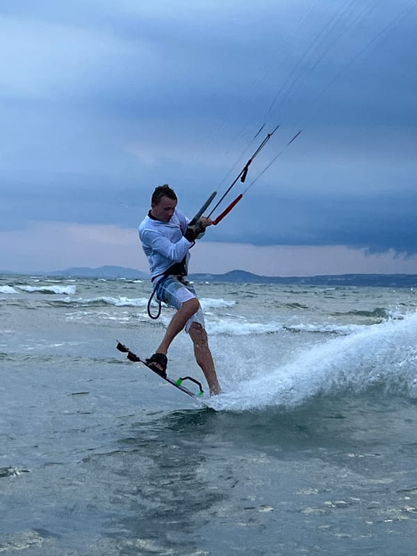 Kitesurfers hit choppy Mũi Né waters under a stormy sky.