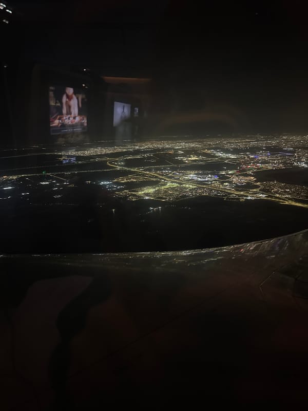 Nighttime Osaka skyline viewed from observation deck through reflective surface