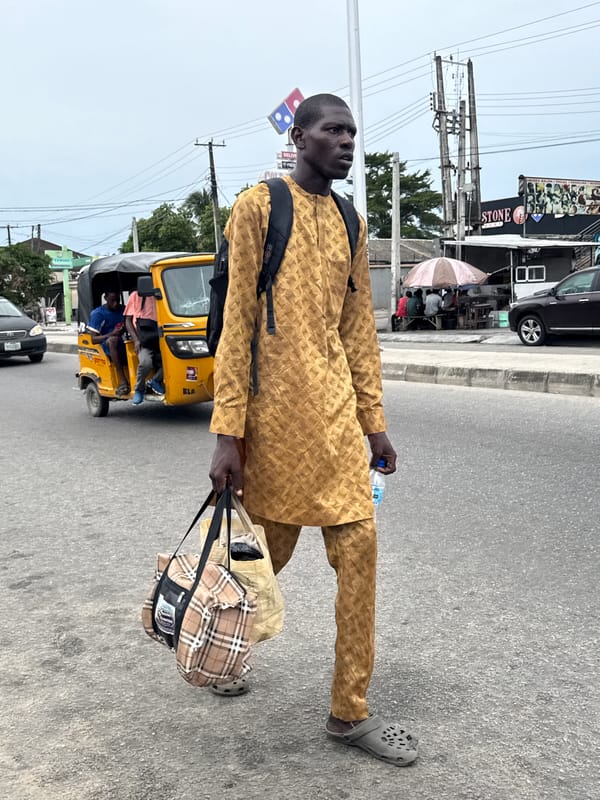 Man walks roadside carrying bag, water bottle in Ado