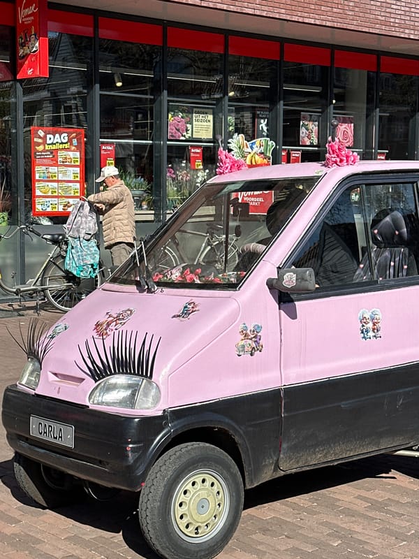 Contrasting vehicles spotted in Amsterdam: decorated microcar, Mazda wheel