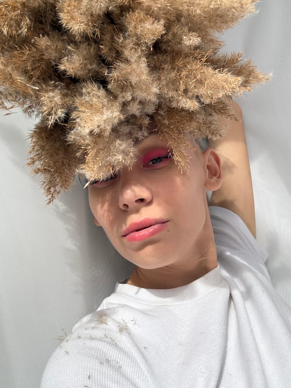 Woman with pink makeup poses indoors with pampas grass