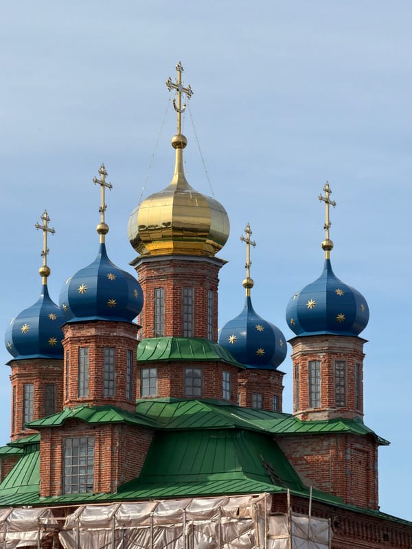 Orthodox church with blue domes beside a calm riverside