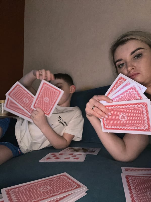 Woman and boy play cards indoors in Chaikovsky, Russia
