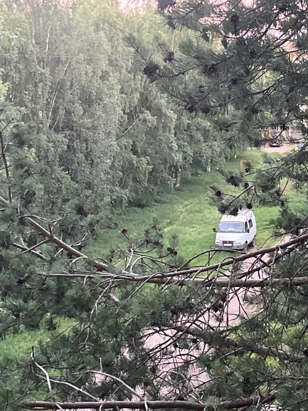 Elevated surveillance of vans parked on a rural dirt path at dusk