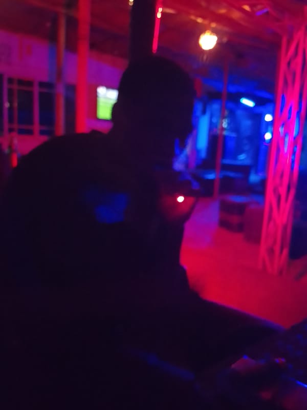Evening social gathering at neon-lit bar in Yelwa, Nigeria