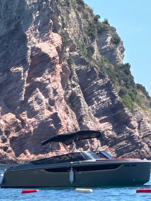Beach day with boats, paddleboarding and cocktails by rocky cliffs