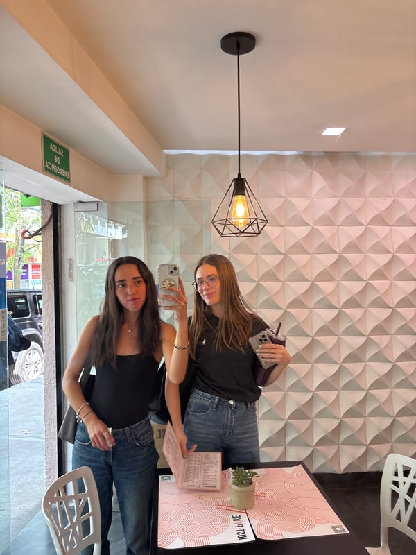 Two women photographing inside restaurant through window