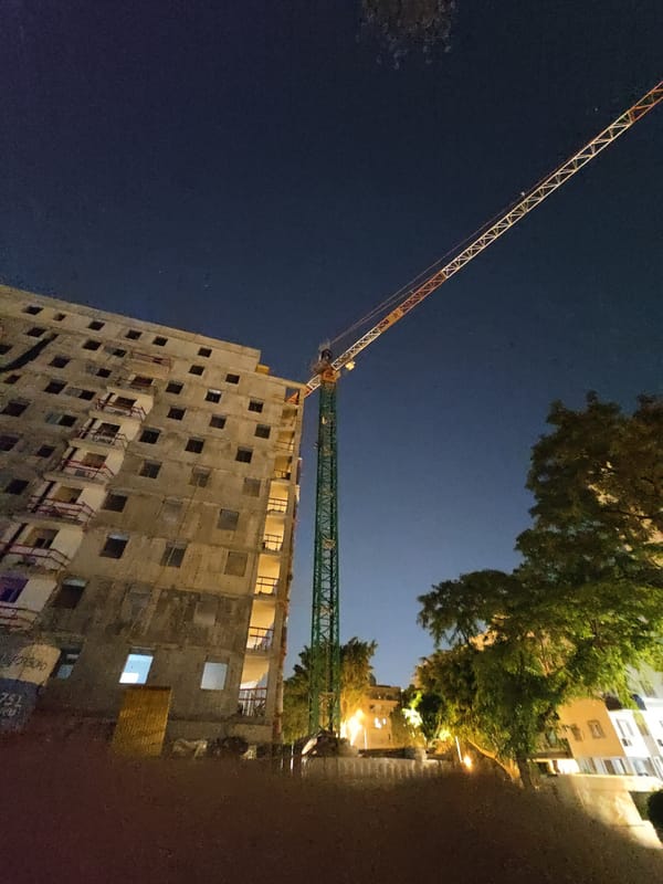 Construction crane over unfinished high-rise in Petah Tikva at night