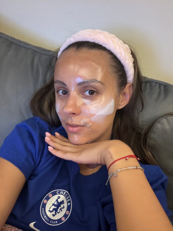 Woman in facial mask relaxes on couch wearing Chelsea shirt