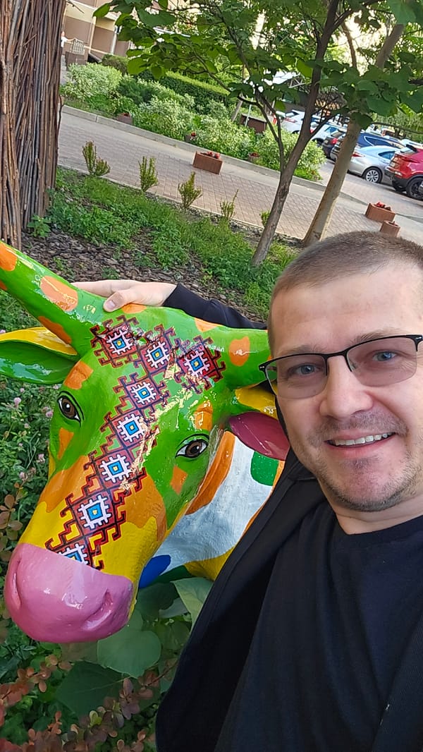 Selfie with painted cow sculpture and flower planters in Kyiv