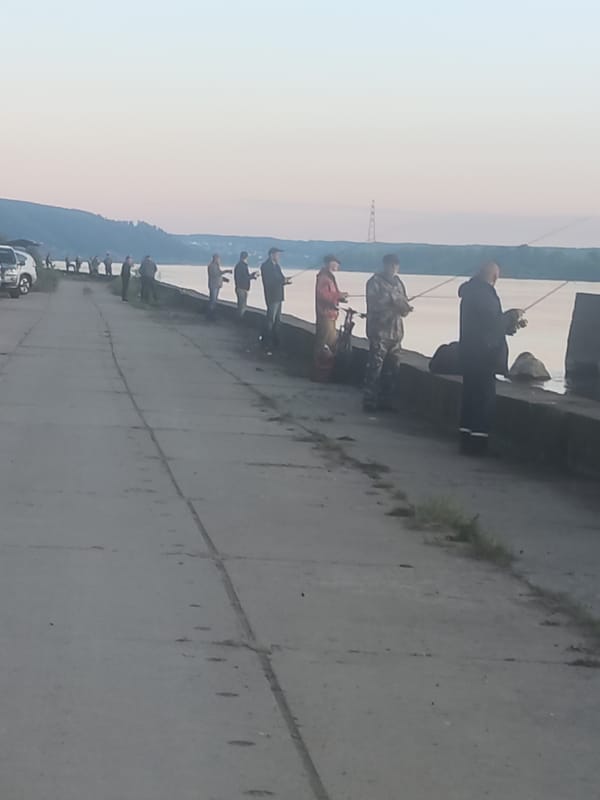Fishermen gather along waterfront during golden hour sunset