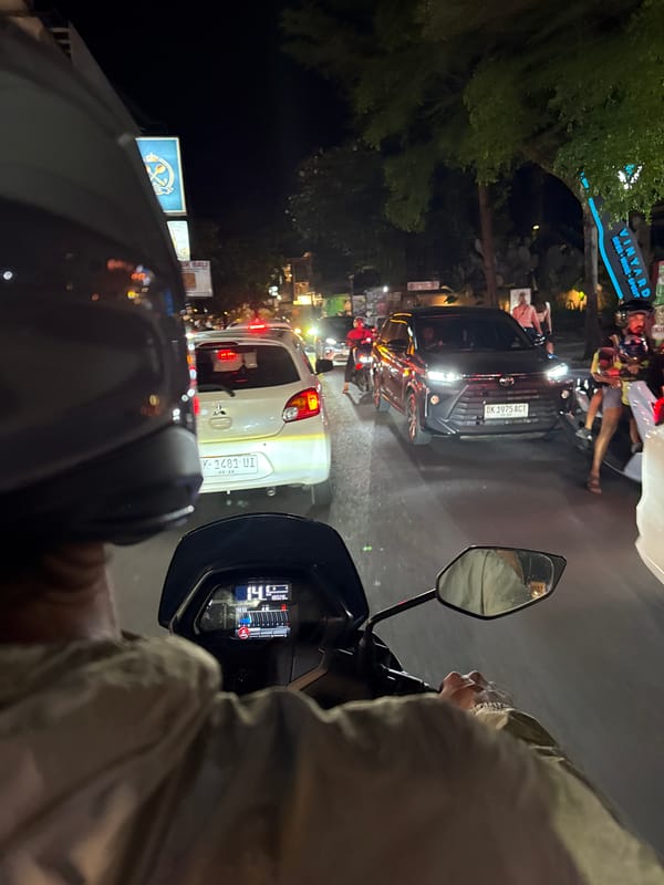 Motorcyclist navigates dense nighttime traffic in Ubud District