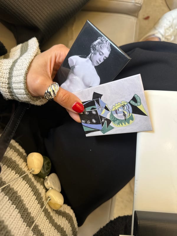 Woman examines phone and art magnets at London table