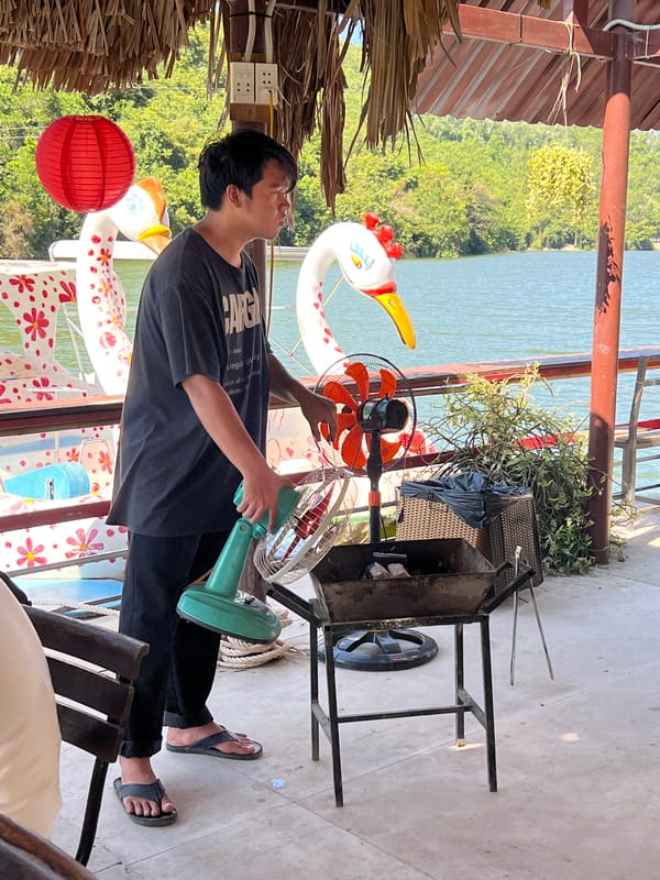 Waterfront barbecue dining scene with friendly dog in Nha Trang