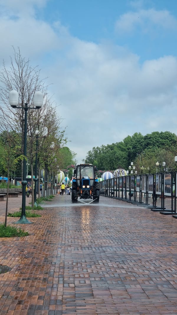 Moscow park morning: metro monument, wet brick paths, city backdrop